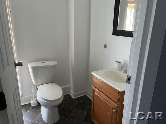 half bath featuring tile patterned floors, vanity, and toilet