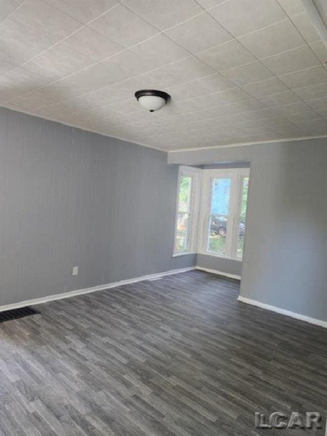 unfurnished room with baseboards and dark wood-type flooring