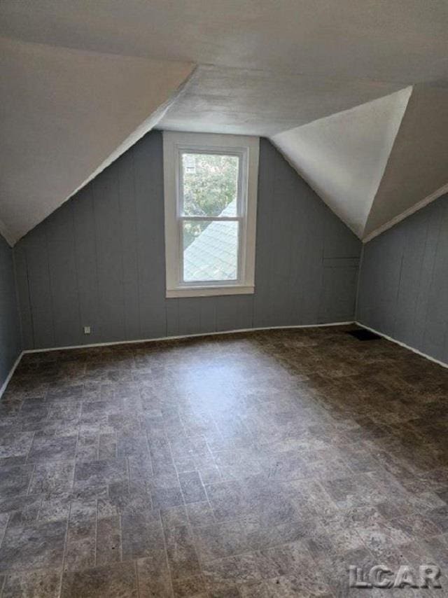 bonus room with vaulted ceiling and a decorative wall