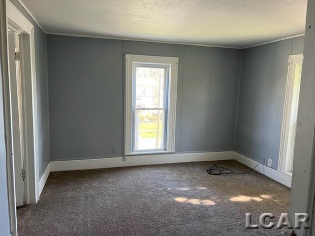 carpeted empty room with baseboards and a textured ceiling