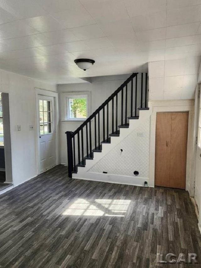 unfurnished living room featuring stairs and dark wood-style floors