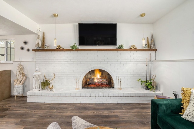living area with a brick fireplace and wood finished floors