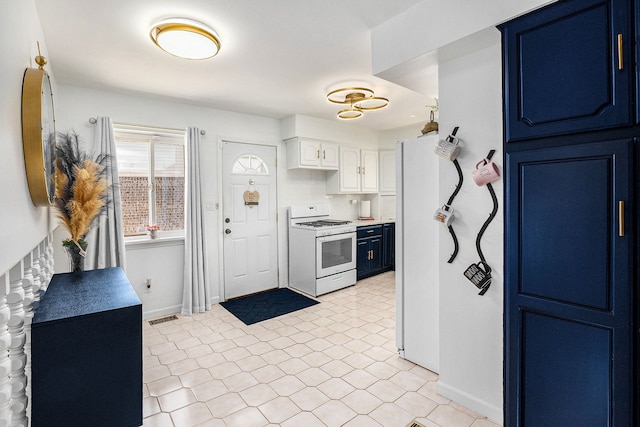 kitchen featuring gas range gas stove, light tile patterned flooring, baseboards, visible vents, and blue cabinetry