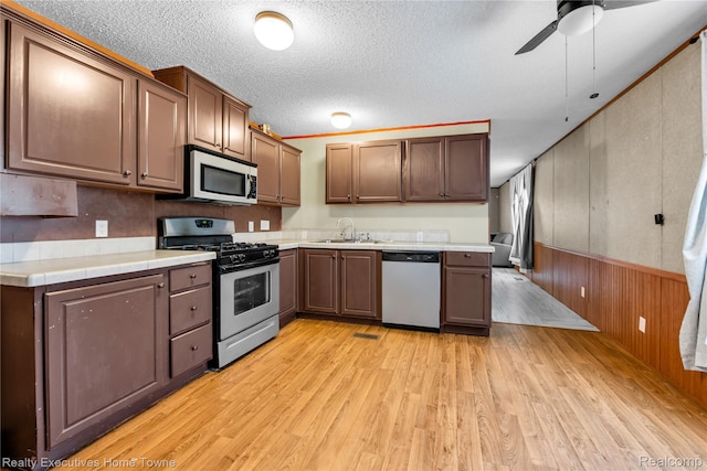 1822 Elizabeth Ter, Madison Heights, MI 48071 - kitchen with appliances with stainless steel finishes, a sink, light wood finished floors, a textured ceiling, and wood walls
