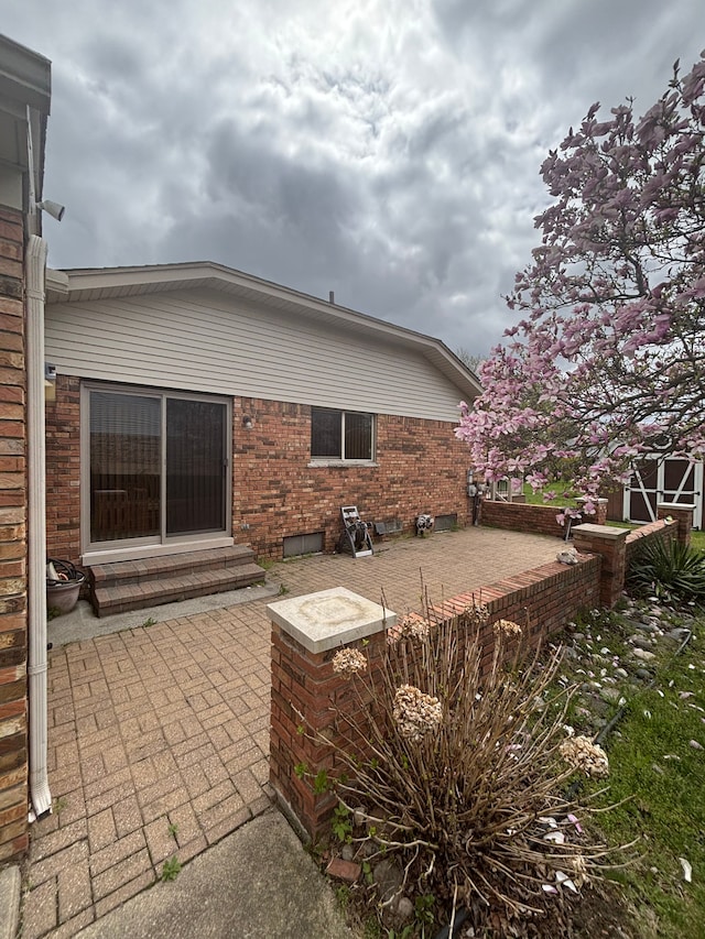 back of property with a patio, entry steps, and brick siding