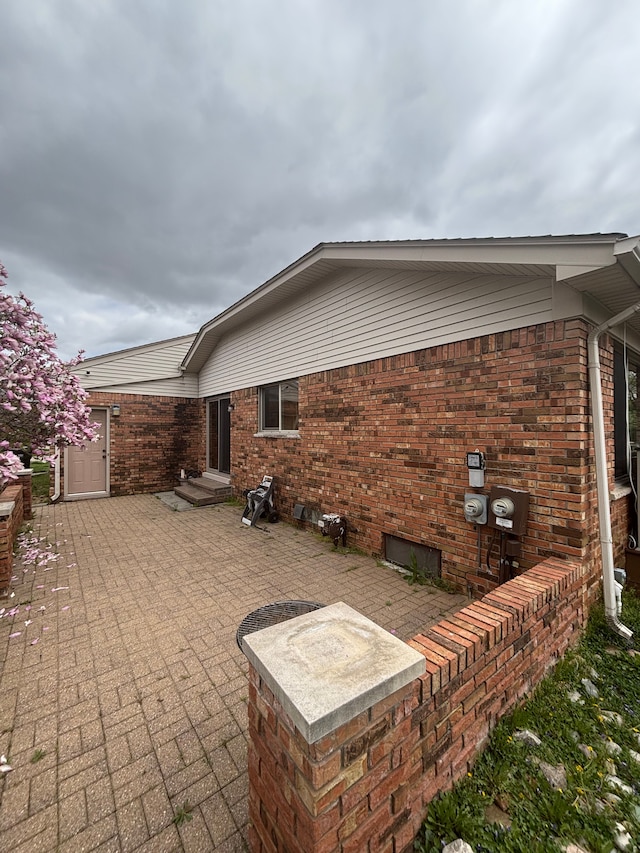 rear view of property with brick siding and a patio area