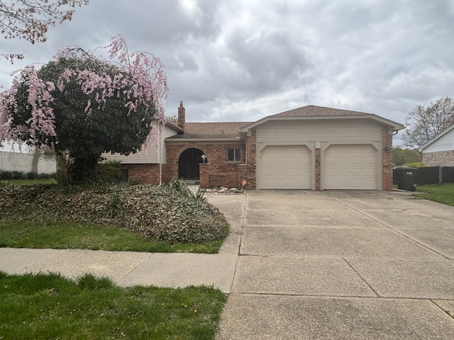single story home with concrete driveway, a chimney, an attached garage, and brick siding