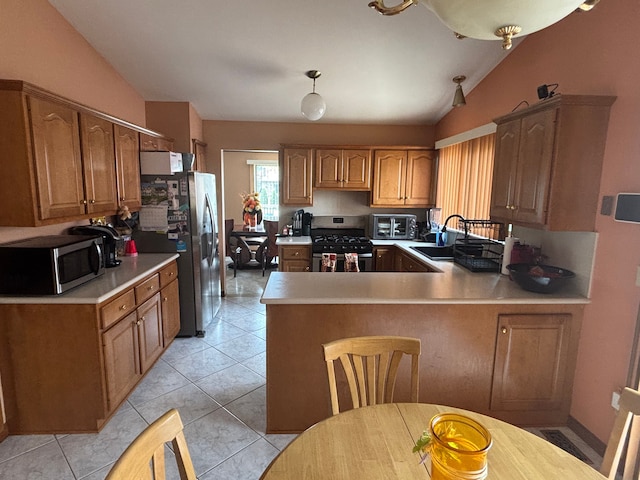 kitchen with lofted ceiling, a sink, stainless steel appliances, light countertops, and a peninsula