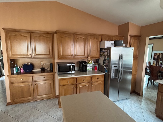 kitchen with stainless steel appliances, light countertops, brown cabinets, vaulted ceiling, and light tile patterned flooring