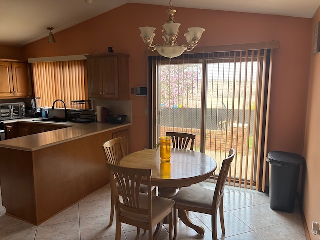dining room featuring a toaster, light tile patterned flooring, a notable chandelier, and lofted ceiling