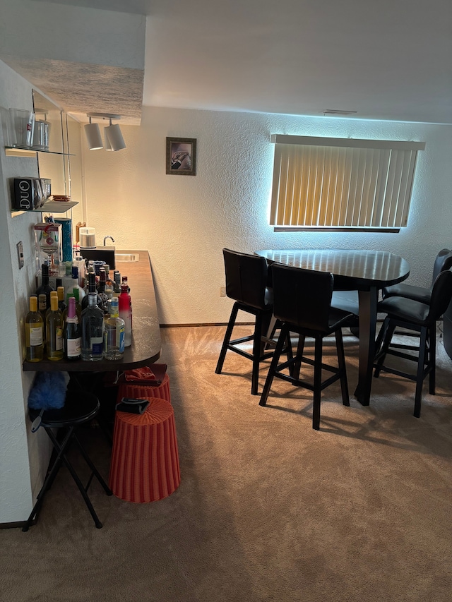 carpeted dining space featuring a textured wall and baseboards