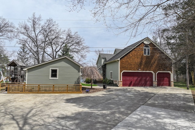 view of property exterior with stone siding, a detached garage, and concrete driveway