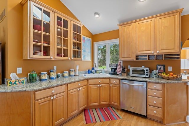 kitchen with stainless steel dishwasher, light stone counters, a sink, light wood-type flooring, and lofted ceiling