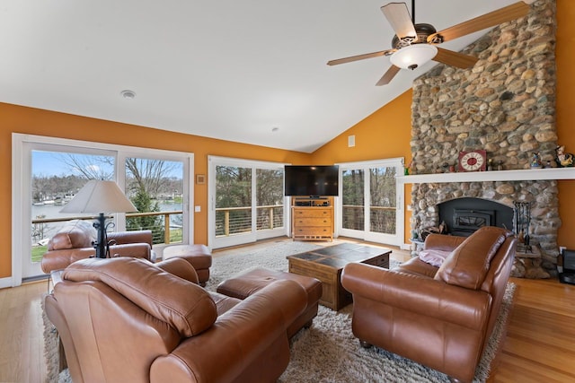 living area with a ceiling fan, wood finished floors, a wealth of natural light, and high vaulted ceiling