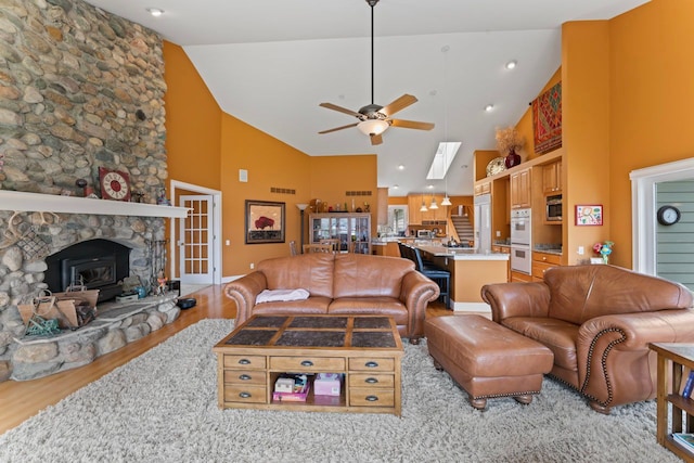 living area featuring visible vents, light wood-type flooring, a ceiling fan, and high vaulted ceiling