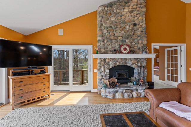living area with a wood stove, high vaulted ceiling, and wood finished floors
