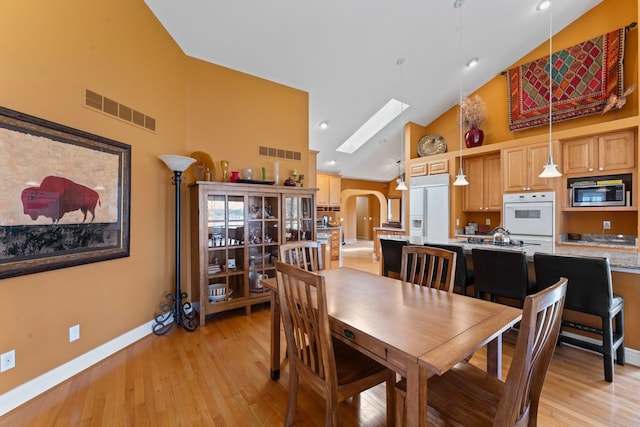 dining room featuring visible vents, high vaulted ceiling, a skylight, and baseboards