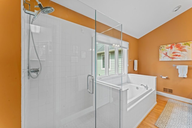 bathroom with visible vents, lofted ceiling, wood finished floors, a shower stall, and a garden tub