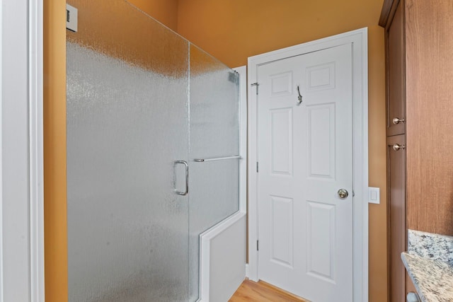 bathroom with wood finished floors and a stall shower