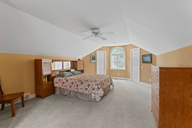 bedroom featuring vaulted ceiling, two closets, light colored carpet, and multiple windows