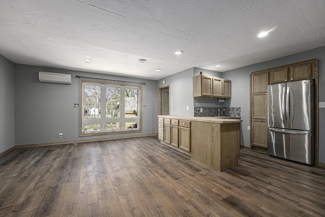 kitchen with a textured ceiling, freestanding refrigerator, light countertops, dark wood finished floors, and a wall unit AC