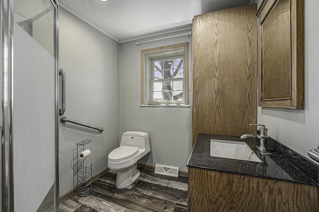 bathroom with wood finished floors, visible vents, toilet, vanity, and baseboards