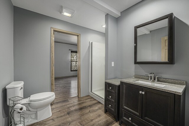 full bathroom with a shower stall, wood finished floors, toilet, and vanity
