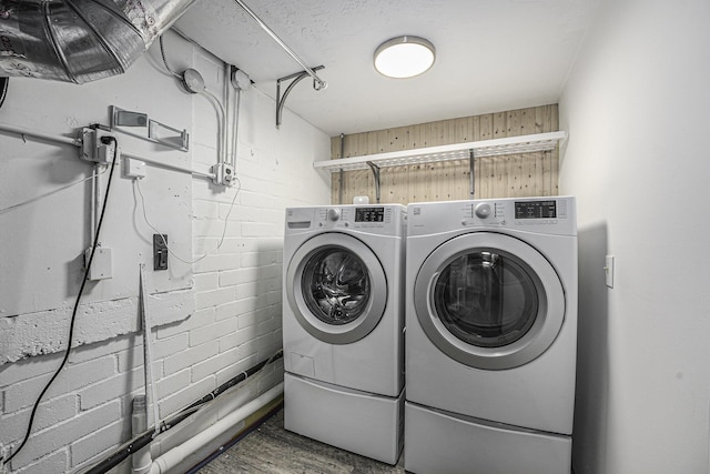 laundry area with concrete block wall, independent washer and dryer, and laundry area