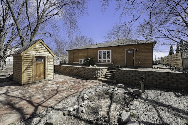 rear view of house featuring fence, an outbuilding, and a storage shed