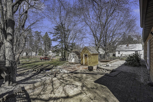 view of yard featuring an outdoor structure, fence, a patio area, and a storage shed