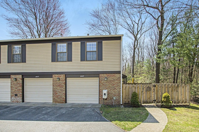 3669 Brentwood St, Norton Shores, MI 49441 - view of side of property with an attached garage, driveway, fence, and brick siding