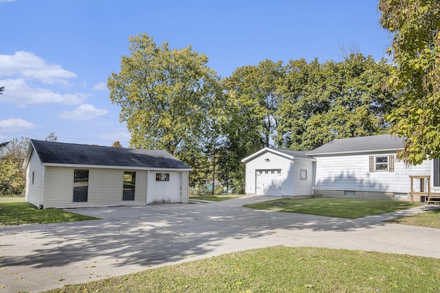 65 N Lake St, Grant, MI 49327 - view of front of house featuring driveway, an outdoor structure, a front lawn, and a garage