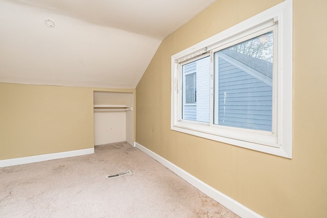additional living space with carpet flooring, baseboards, visible vents, and lofted ceiling