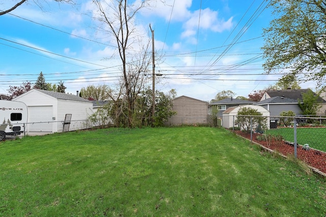 view of yard featuring a detached garage, an outdoor structure, and a fenced backyard