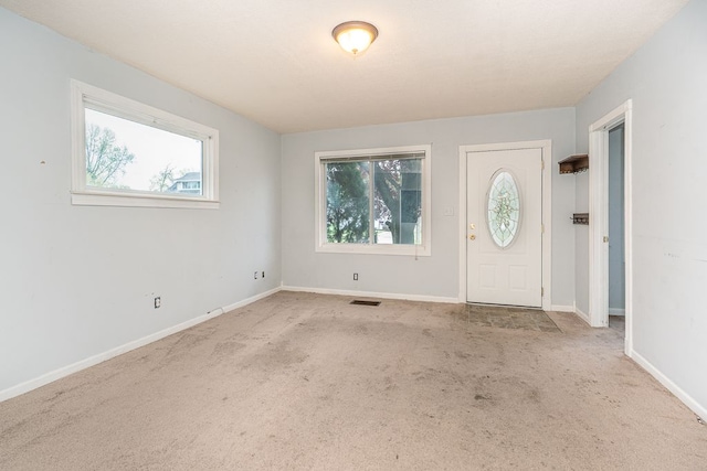 foyer featuring carpet floors, visible vents, and a wealth of natural light
