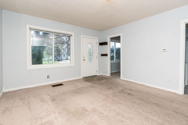 foyer with visible vents, baseboards, and carpet floors