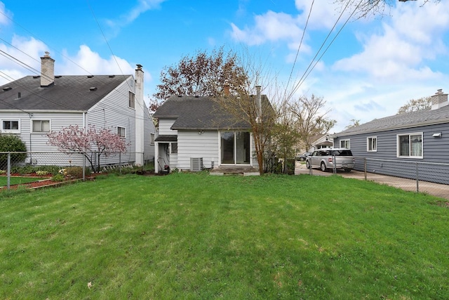 rear view of property with a yard, central AC, and fence