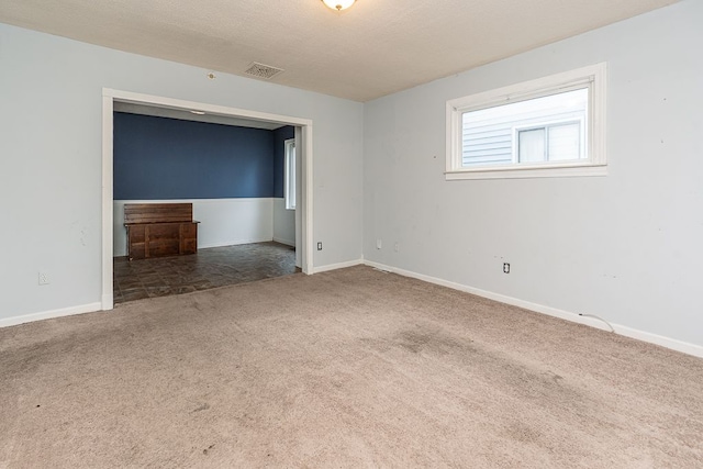 carpeted spare room with visible vents and baseboards