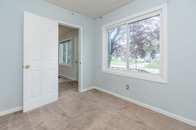 unfurnished bedroom featuring carpet floors, baseboards, and multiple windows
