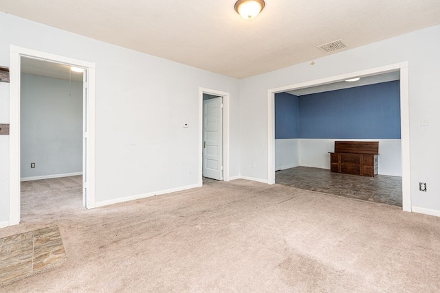 carpeted empty room featuring baseboards and visible vents