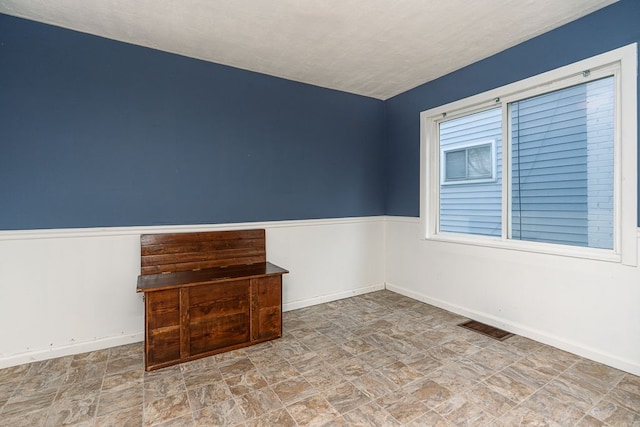 spare room with baseboards, visible vents, and stone finish floor