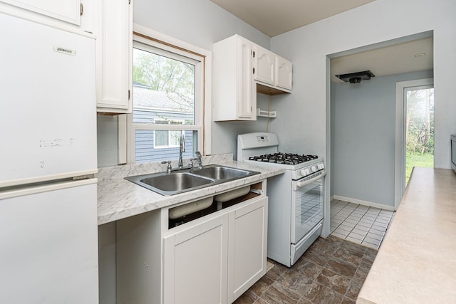 kitchen with light countertops, white appliances, a sink, and white cabinetry