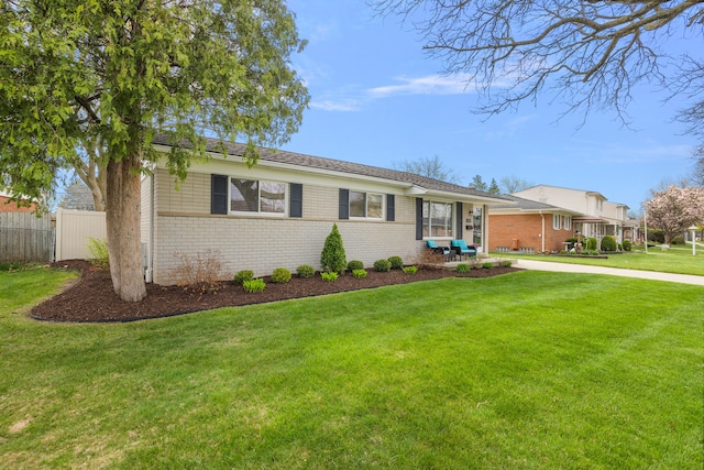 ranch-style house featuring a front yard, fence, concrete driveway, and brick siding
