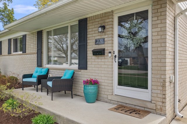 property entrance with brick siding and a porch