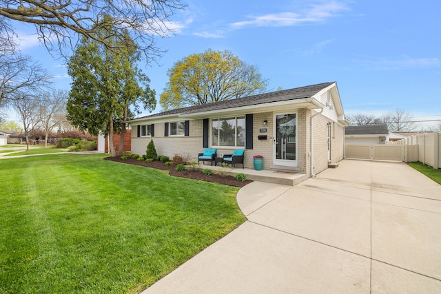 view of front of home with driveway, fence, a front yard, and brick siding