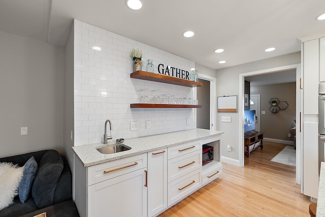 interior space featuring light stone counters, open shelves, backsplash, a sink, and black microwave