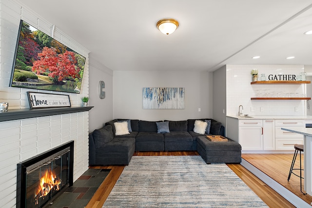 living area featuring recessed lighting, wood finished floors, indoor wet bar, and a brick fireplace