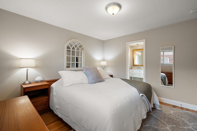 bedroom with wood finished floors, ensuite bathroom, and baseboards