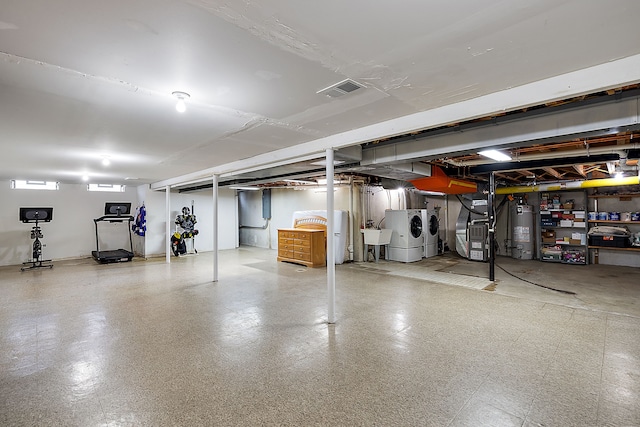 basement featuring heating unit, separate washer and dryer, gas water heater, a sink, and visible vents