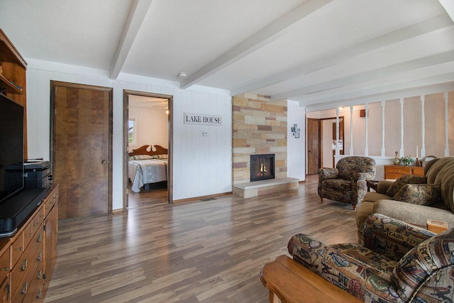living area with wood finished floors, beamed ceiling, and a fireplace